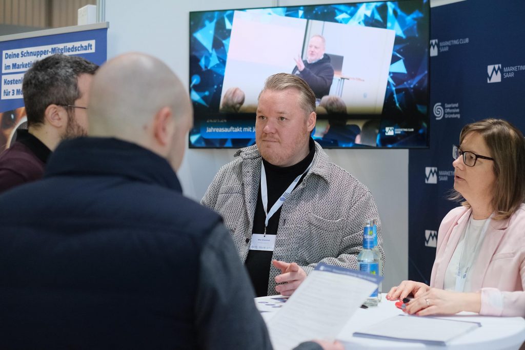 Eine Vertreterin und ein Vertreter des Marketing Club Saar im Austausch mit mehreren Messebesuchern